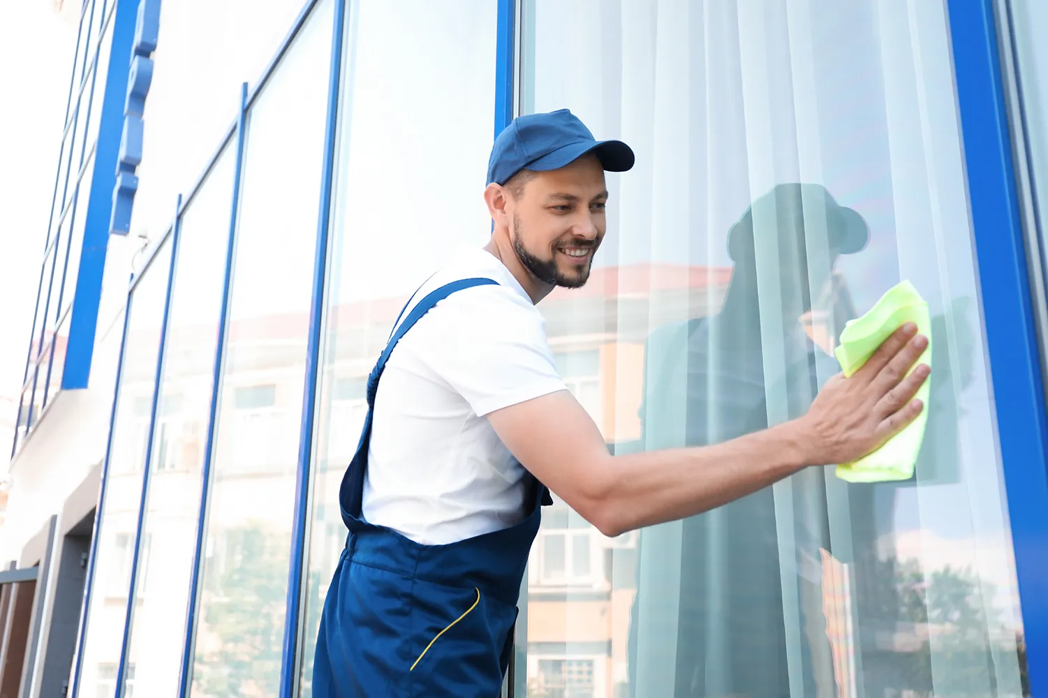 Männlicher Arbeiter wäscht Fensterglas von außen